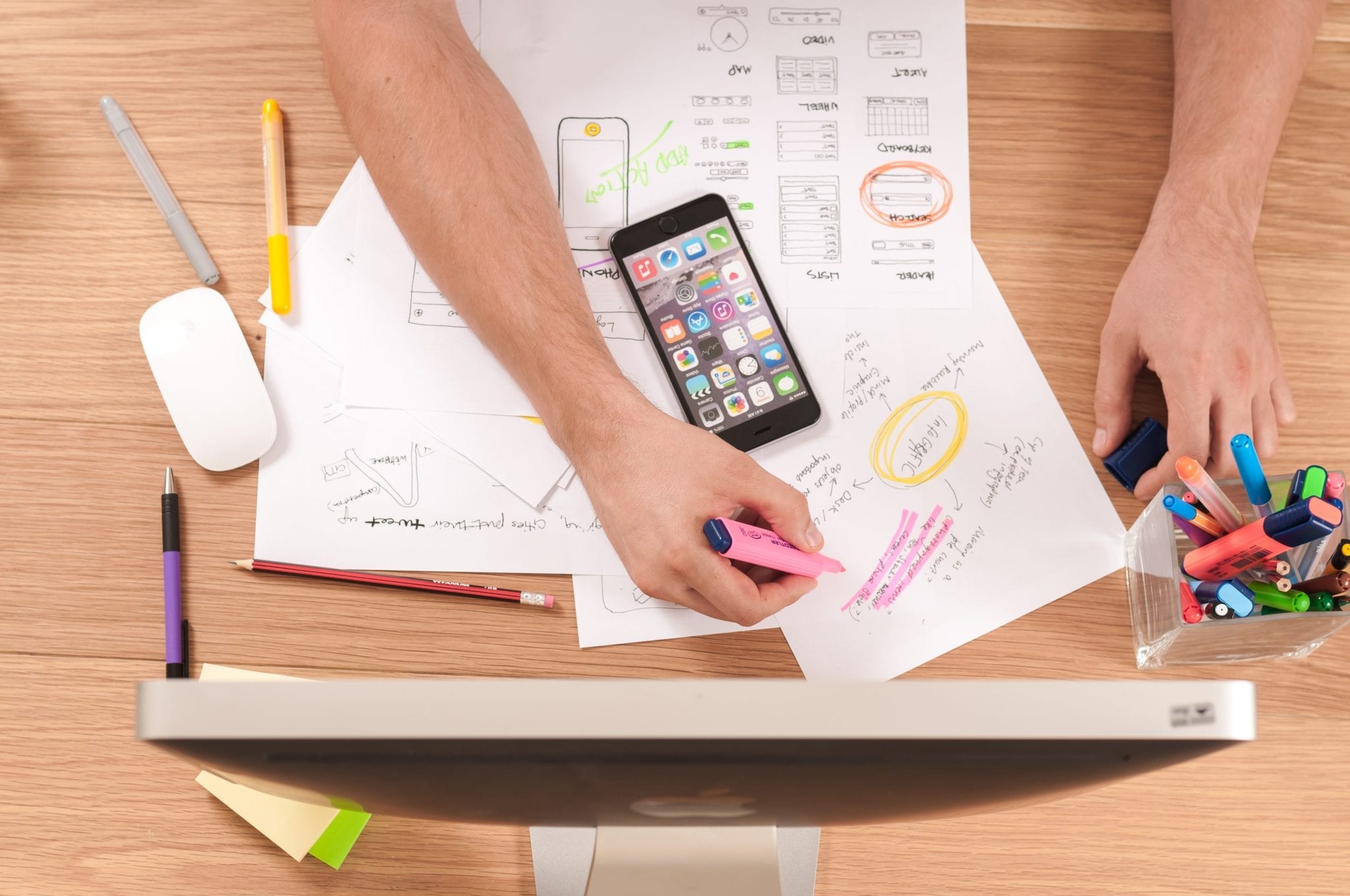 The Testing Process represented by man taking notes in front of computer with cell phone