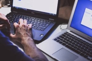 website security represented by person working on side-by-side computers