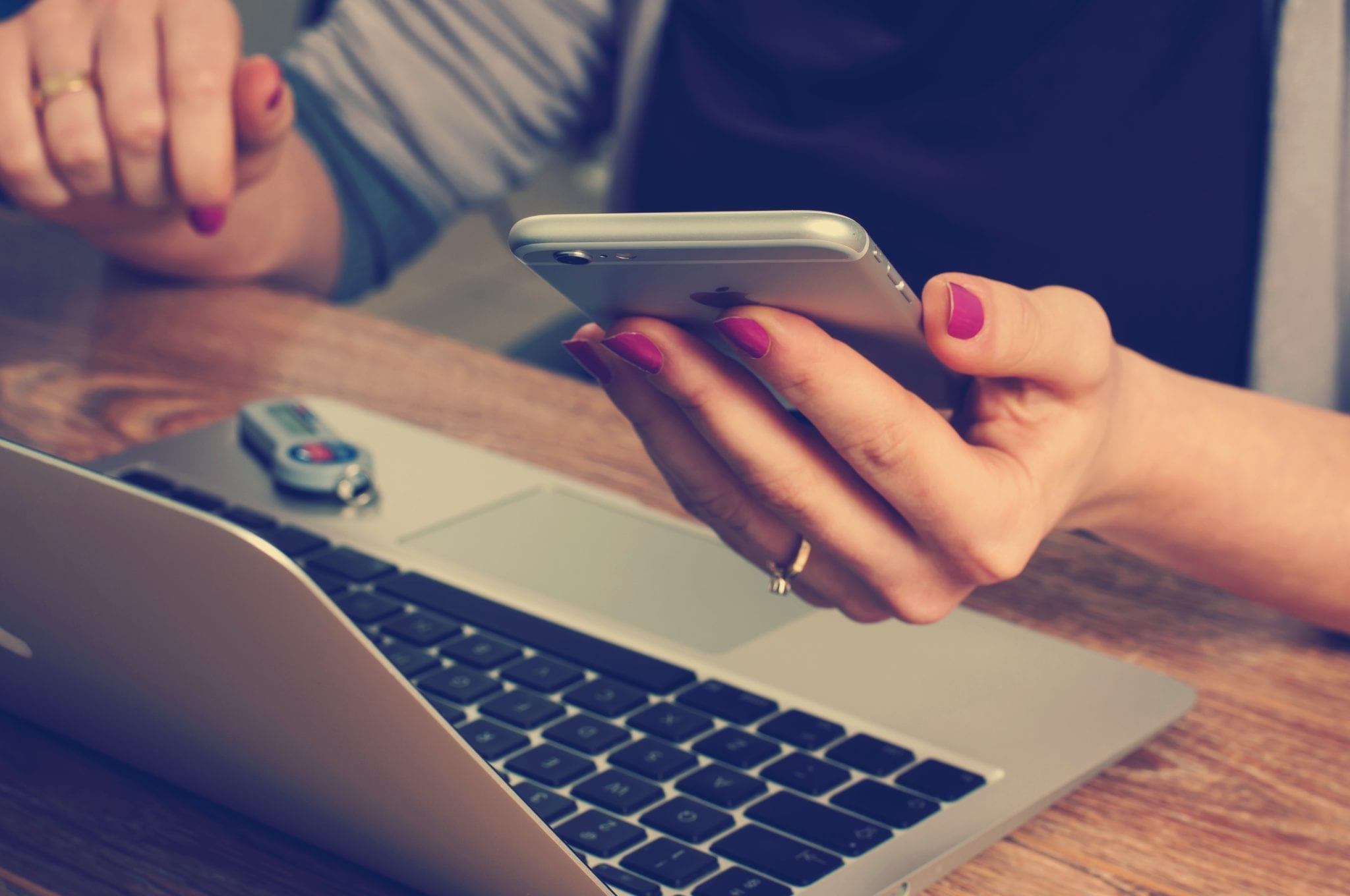 Mobile apps represented by woman holding cell phone while on computer