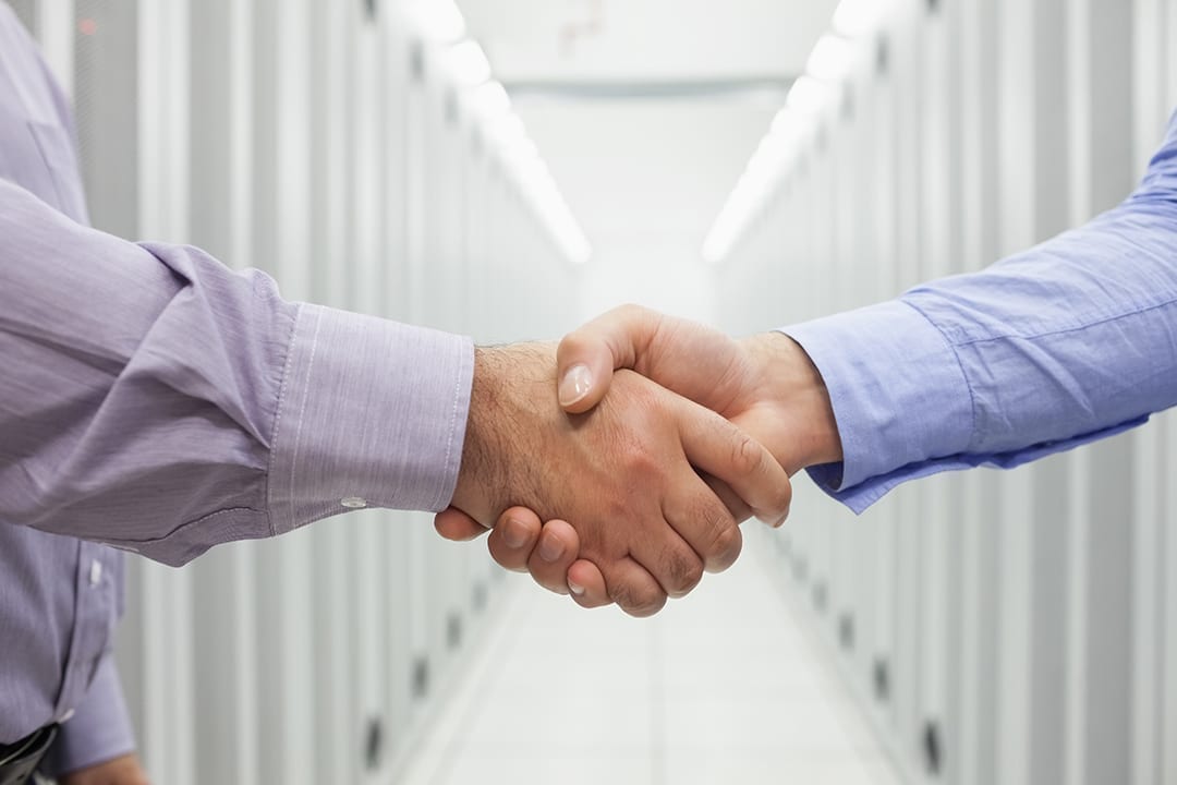 Two men shaking hands in the hallway of data center