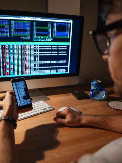 img - serious-developer-in-glasses-using-computer-and-smartphone-